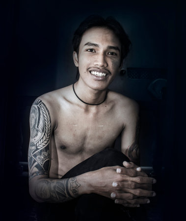 A man sitting at the door with both arms in a tattoo
