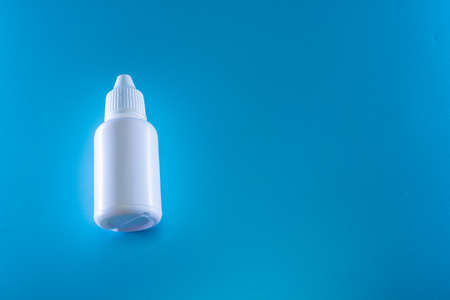 Bottle of white drops on a blue backgroundの写真素材