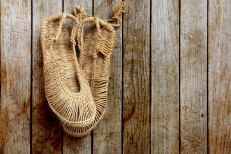 Vintage Chinese straw shoes on wooden wallの写真素材