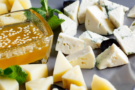 four types of cheese, feta, gorgonzola, parmesan, hard cheese, with honey on a plate, four types of...