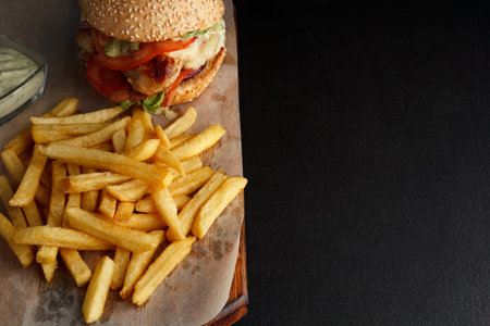 Burger with French fries on a black background. Burger close-up