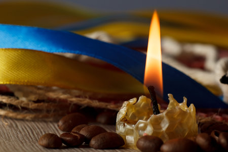 a burning natural wax candle, on the background natural wax with honeycombs and a wick.の写真素材