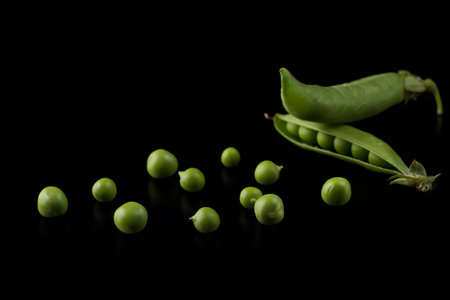 Pea pods on a black background, green peas in a pod on a dark backgroundの写真素材