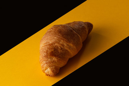 Croissant on a yellow and black background. Delicious pastries on a yellow -black backgroundの写真素材