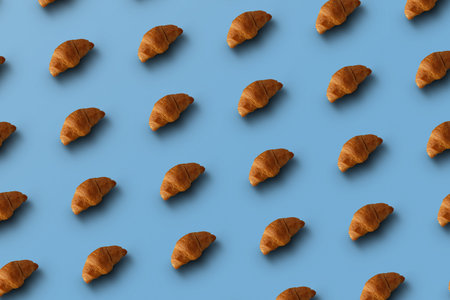 Pattern of baked croissants with a blue background. Delicious pastries.の写真素材