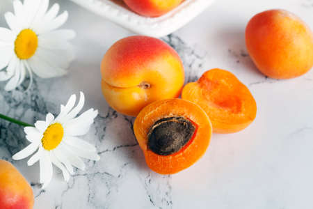 ripe apricots with daisies on a white plate on a light background. For calendar, postcard, book, poster.の写真素材