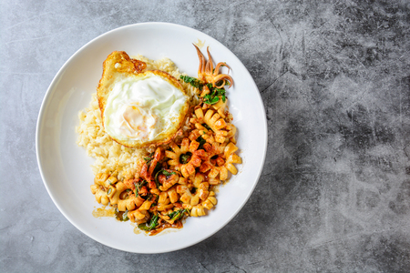 Spicy stir fried squid with basil leaves and chili, Sunny side up egg, served with brown rice. Hot and spicy dish.の写真素材
