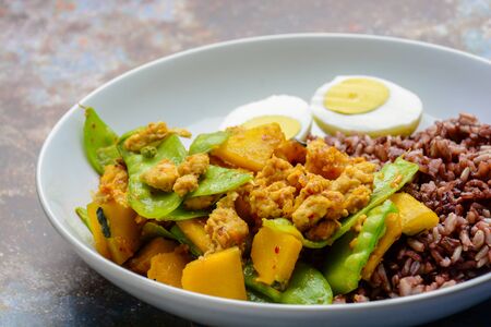 Stir Fry Snow Peas with pumpkin and chicken, served with brown rice and boiled eggの写真素材