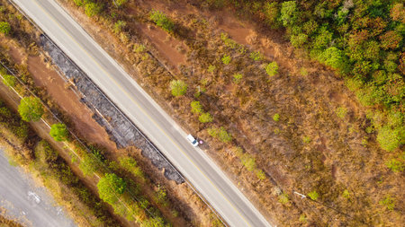 Aerial view of the green and brown forest and asphalt road in the summer, Top view forest road trip...