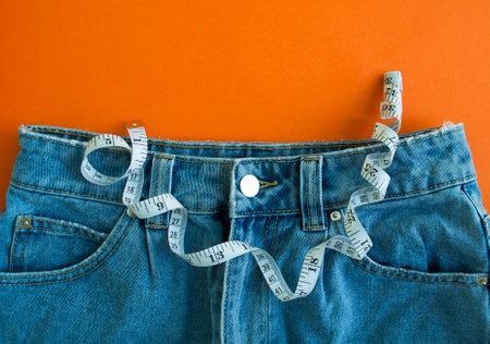 Jeans and centimeter tape on an orange background.の写真素材