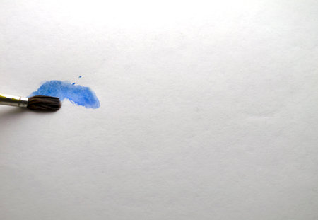 Brush and blue watercolor paint. The brush draws on white paper with blue watercolor paint.の写真素材