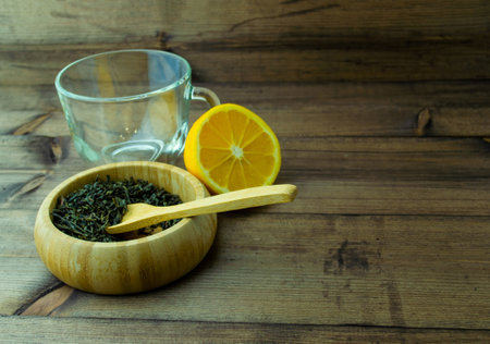 Glass mug with dried green tea and cut lemon. Glass mug with dried green tea and lemon on a wooden table.の写真素材