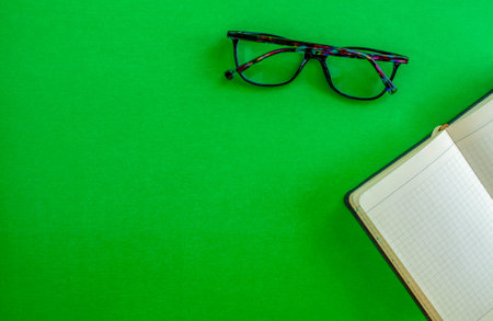 desktop. Notebook glasses on a green background, top view. Mockup diary. Business, freelancing, back to school.の写真素材