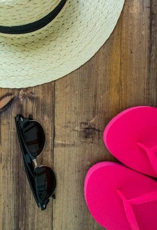 Summer vacation, flat lay. Hat, flip flops and swimsuit on a dark wooden background, vertical background. background for advertising.の写真素材