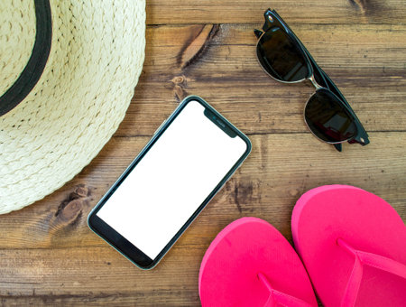Mockup, smartphone, sunglasses, flip flops and hat on wooden background. summer holiday. background for advertising.の写真素材