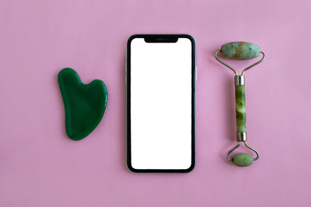Mockup, smartphone and jade massagers on a pink background. background for advertising.の写真素材