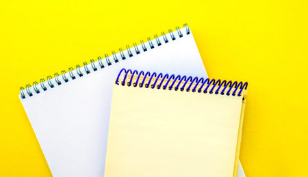 White and beige notepads on a yellow background. School white and beige notebooks on a yellow background.の写真素材