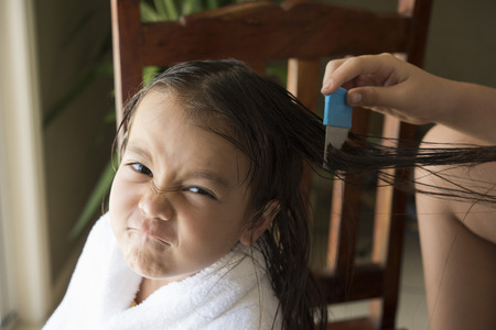a girl is upset face, she is doing head lice treatmentの写真素材