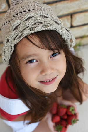 a girl is holding many strawbeerries.の写真素材