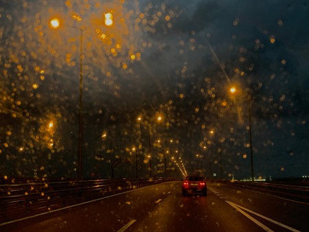 Night road in the rain through the glass lights glare
