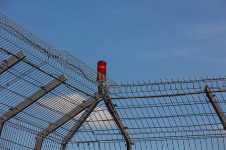 the red signal of the beacon on the fence against the blue sky