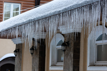 Large icicles on the roof of the house. Danger from falling iciclesの写真素材