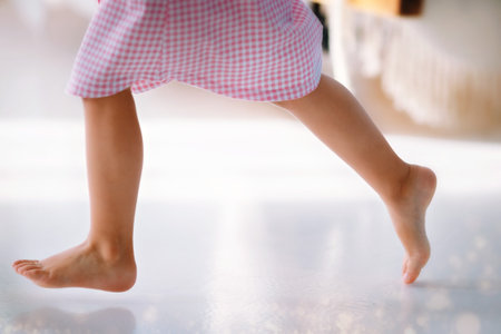 Bare feet of a girl in close-up on a white clean floor. A girl in pajamas runs through the houseの写真素材