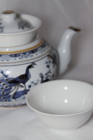 White porcelain teapot with dark blue drawing and two white drinking bowls, a side view, macroの写真素材