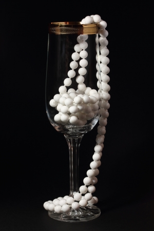Glass and white necklace on a black backgroundの写真素材