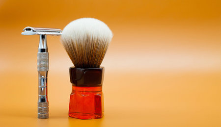 Metal shaving razor and brush close-up. Yellow background with copy space.