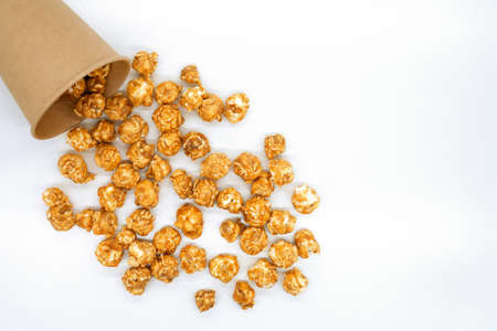 Popcorn with caramel close-up. Popcorn spilled out of a paper cup. White background. Top view.の写真素材