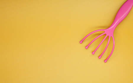 Headmassage tool. Manual scalp massager. Yellow background with place for text. Pink massager.の写真素材