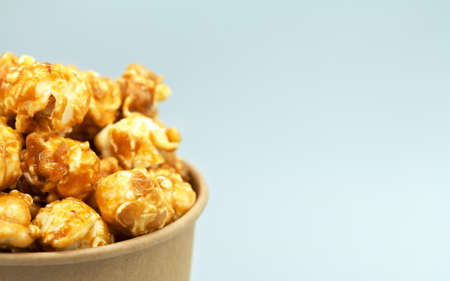 Caramelized popcorn in a paper cup. Close-up, macro photography. Cropped in half. Free space for text on the right.の写真素材