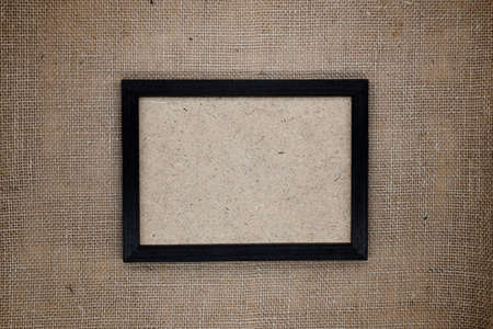 Mockup, composition from natural materials, eco concept. Dark brown wooden frame on burlap. Inside the frame is a wooden fiber base.の写真素材