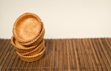 Five shortcrust pastry tartlets on a bamboo mat. Free space for text.