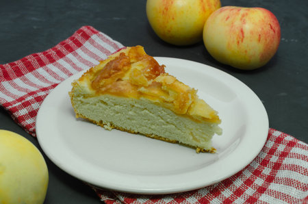 delicious piece of homemade apple pie closeup on a white plate on a dark background with fresh...