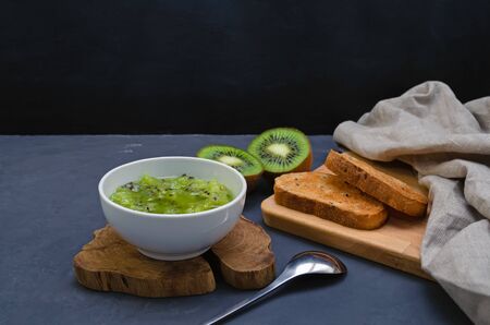 Kiwi jam and fresh kiwi fruits on a dark background. Healthy eating and dieting concept. with copy space.の写真素材