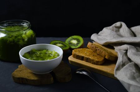 Kiwi jam and fresh kiwi fruits on a dark background. Healthy eating and dieting concept. with copy space.の写真素材