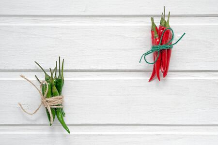 Colorful red and green chili peppers over white wooden background. Top view with copy space.の写真素材