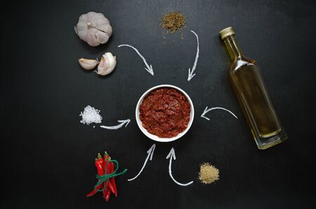 Harissa ingredients for cooking hot chilli red pepper, coarse sea salt, garlic, cumin zira, olive oil, ground coriander on a dark slate background. adjika, muhammara. Eastern cuisine.の写真素材