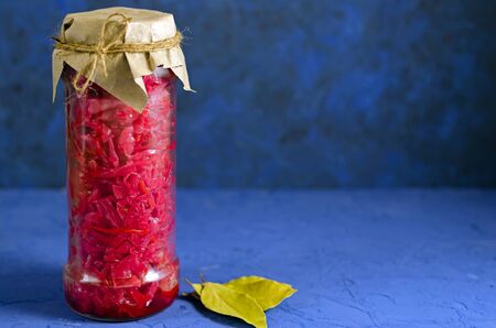 fermented pickled vegetables. red cabbage with beets and bay leaves in a glass tall jar on a classic blue background with copy spaceの写真素材
