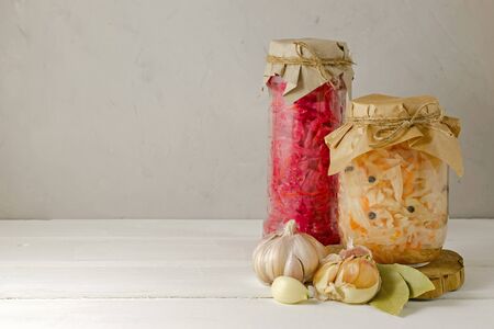 fermented pickled vegetables in various modern glass jars, ready for closing. white with pepper and red with beetroot cabbage on a light background with copy space. keto diet and healthy food conceptの写真素材