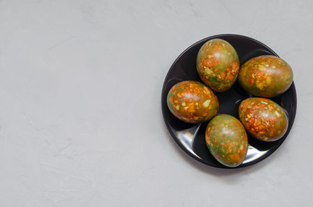 modern trendy marble Easter eggs of original coloring on a dark plate on a light background closeup...