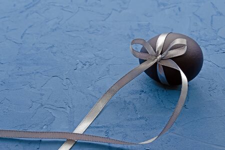 blue egg with a gray satin ribbon on a classic blue background with copy spaceの写真素材