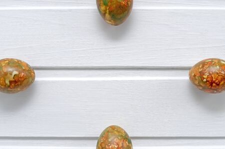 Easter marble fashionable modern multi-colored, originally painted eggs on the sides on a white wooden background with copy spaceの写真素材