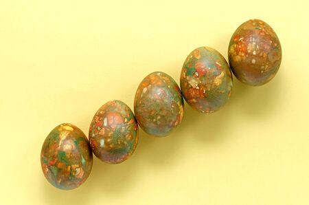 marble modern trendy festive easter eggs are located in the center of the frame in increasing order on a yellow bright background with copy spaceの写真素材