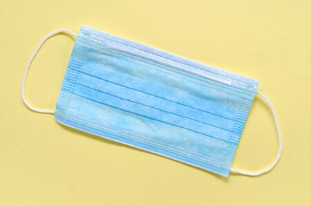 Flu prevention concept. Medical face mask on yellow background top view copy spaceの写真素材