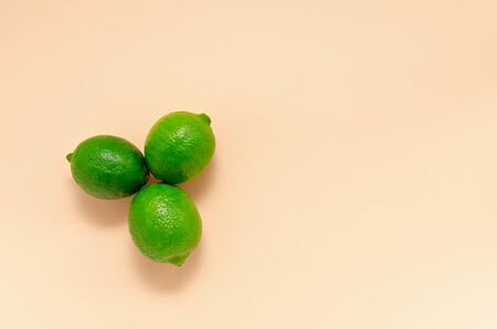 Three fresh juicy bright limes on a gentle peach light background in the form of a flower with copy space. Citrus Vitamin C Healthy Eating. blank for postcards banner and menuの写真素材
