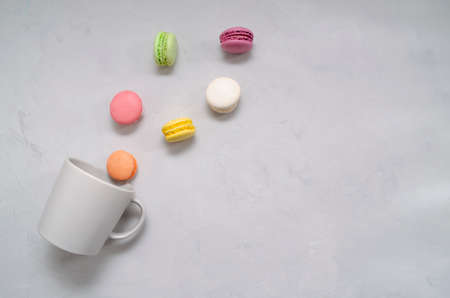 Colorful appetizing delicious crunchy macaroons spilling out of the gray mug on the table.の写真素材