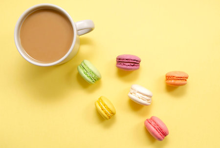 Set of colorful macaroons and coffee. Pastries, pastries and a cup of coffee with milk on a yellow...